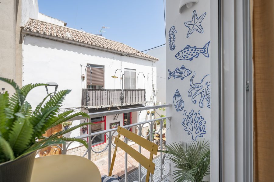 Balcón de Casa Juani con mural marinero pintado y vistas a la calle del casco histórico