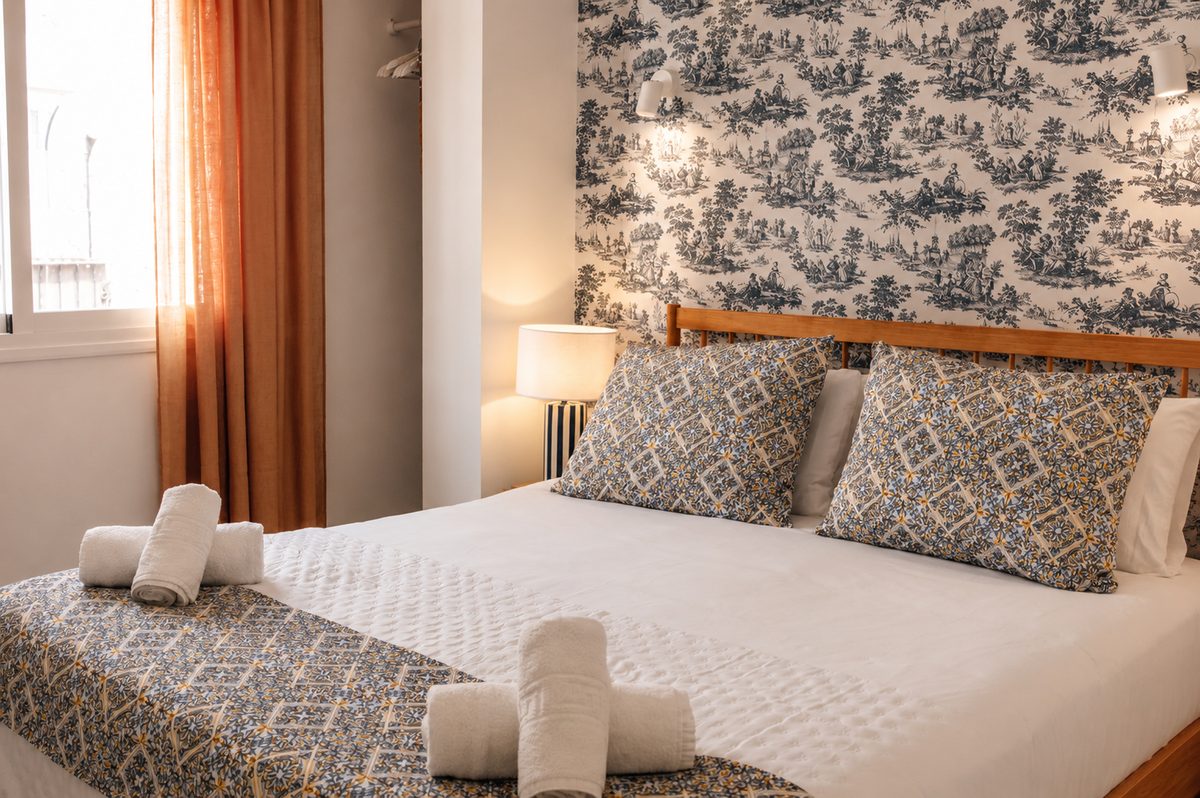 Cama vestida en Casa Juani con toallas dobladas y ropa de cama estampada