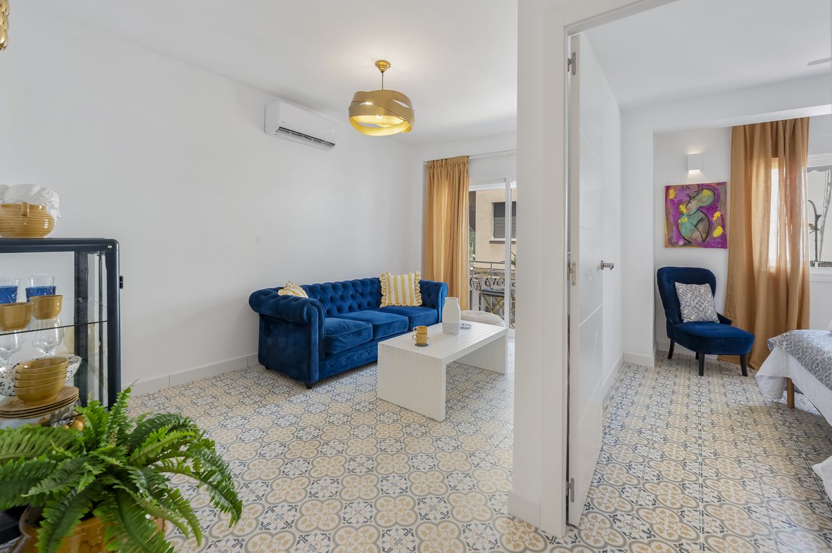 Salón completo de Casa Juani con sofá azul, vitrina y suelo hidráulico