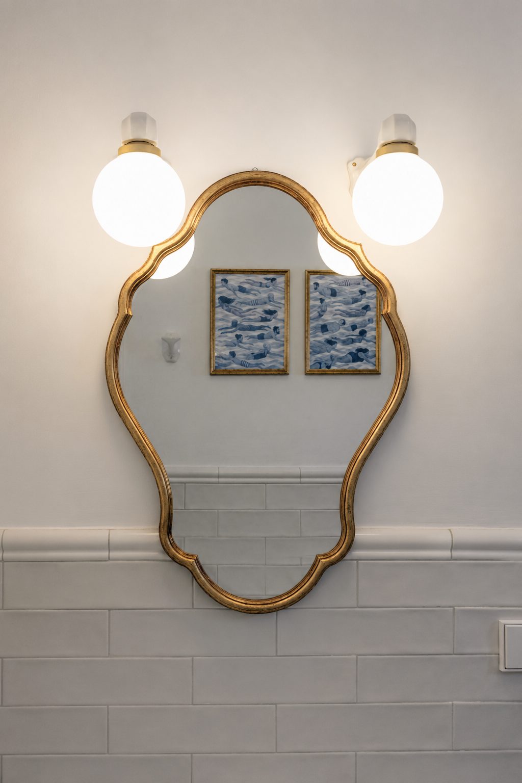 Detalle del baño de Casa Juani, con espejo dorado y láminas de nadadoras